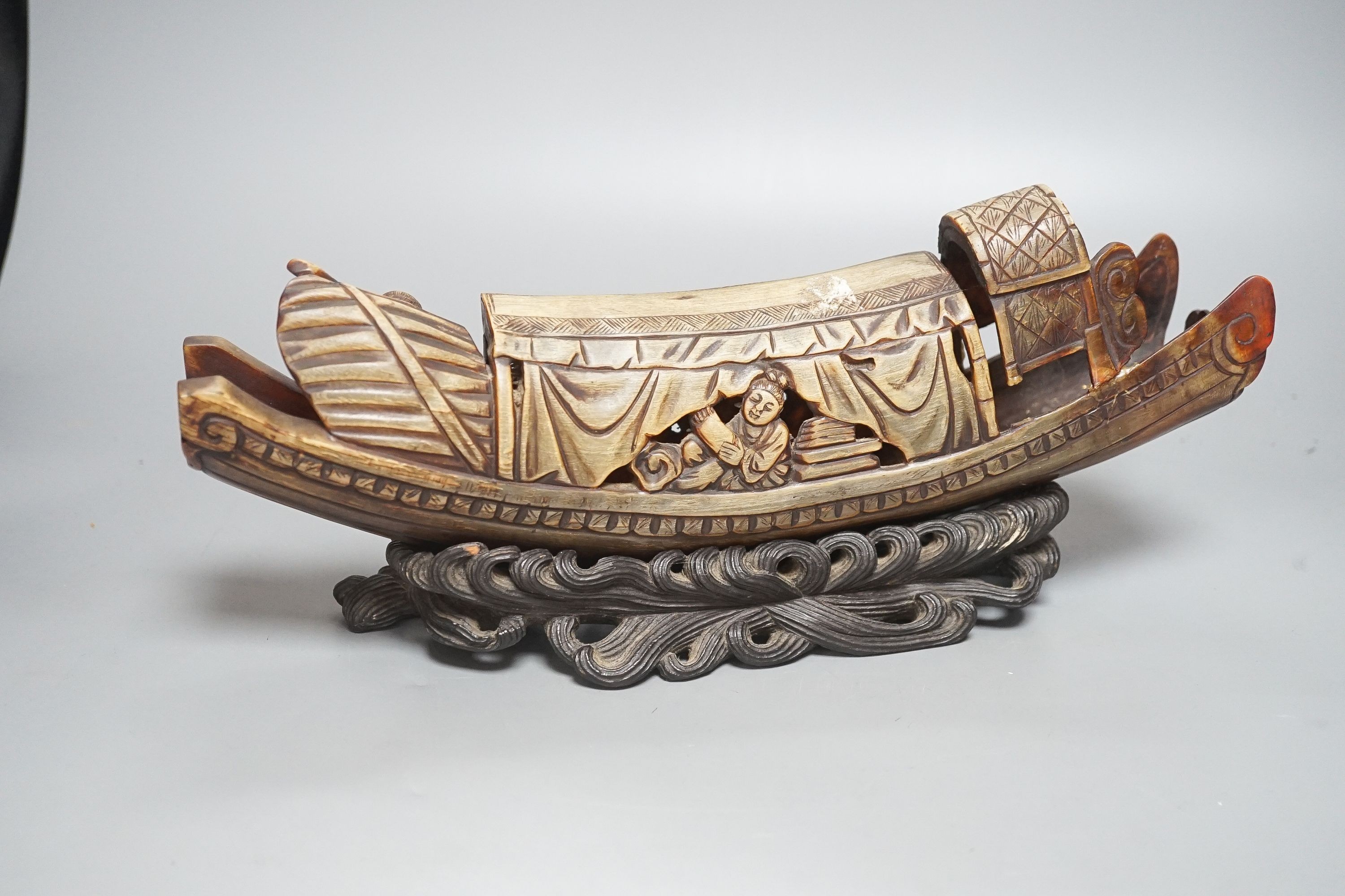 A Chinese horn carving of a junk boat, wood stand, 34cm